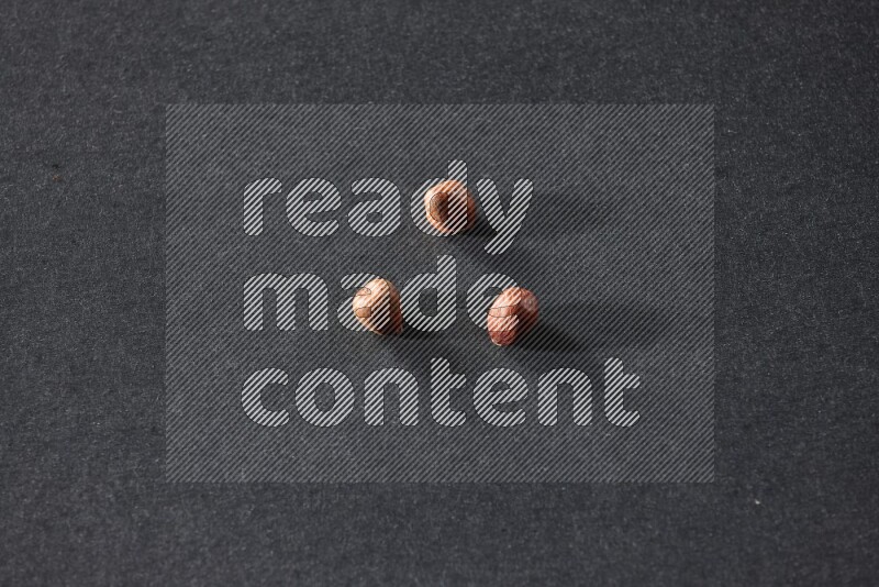 3 peeled hazelnuts on a black background in different angles
