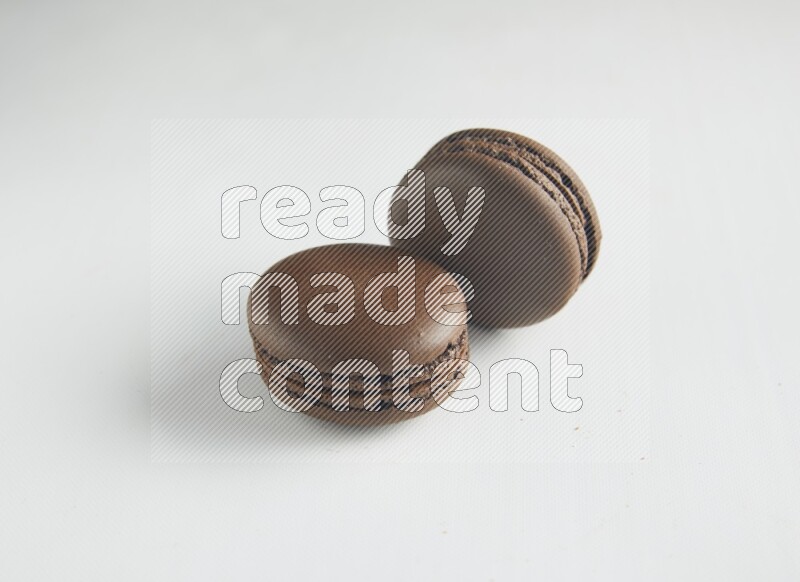 45º Shot of two Brown Dark Chocolate macarons on white background