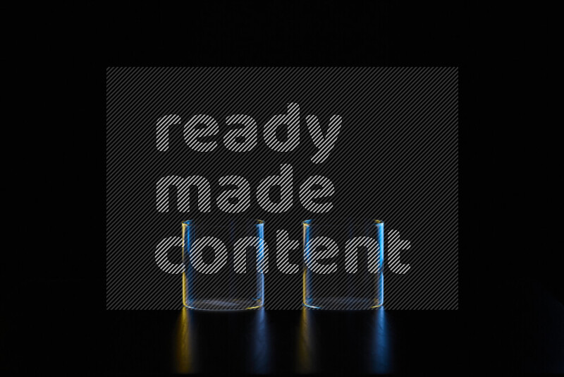 Glassware with rim light in blue and yellow against black background