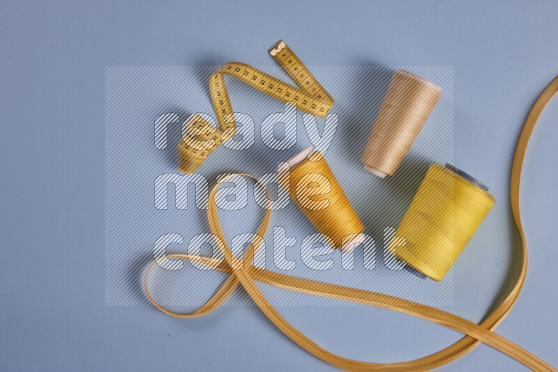 A yellow collection of sewing and tailoring tools arranged on a blue background