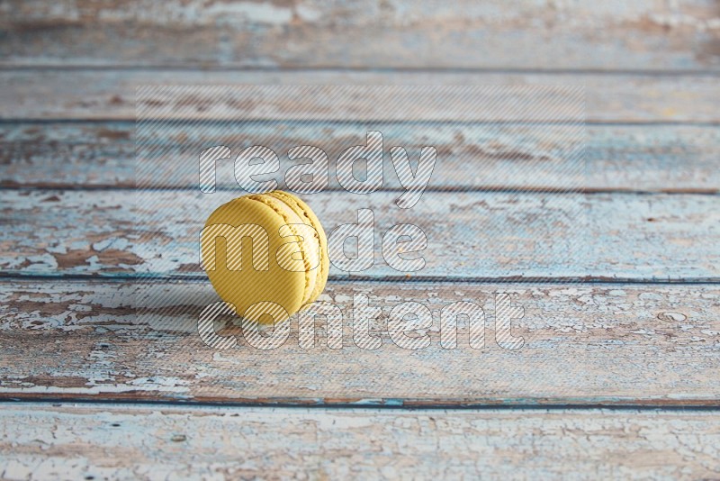 45º Shot of Yellow Lime macaron on light blue wooden background