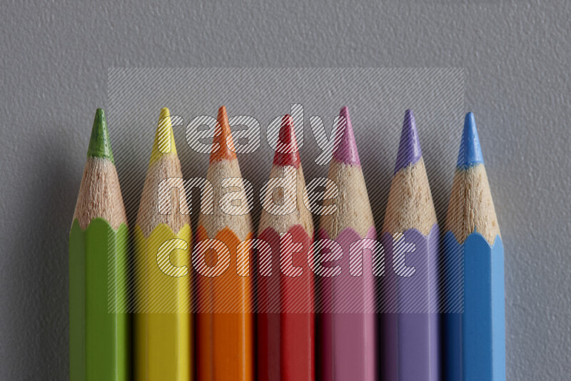 مجموعة من أقلام الرصاص الملونة مرتبة لتعرض تدرجا من الألوان المختلفة علي خلفية رمادية