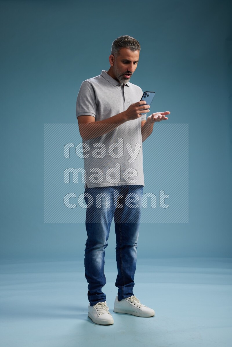 Man Standing texting on phone on blue background