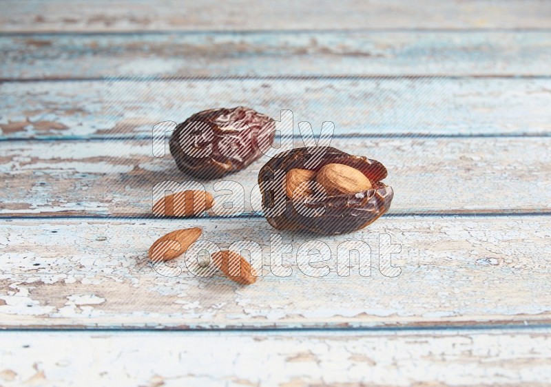 two almond stuffed madjoul dates on a light blue wooden background