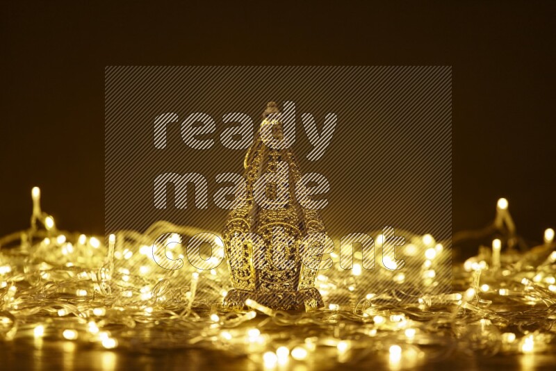 A traditional ramadan lantern surrounded by glowing fairy lights in a dark setup