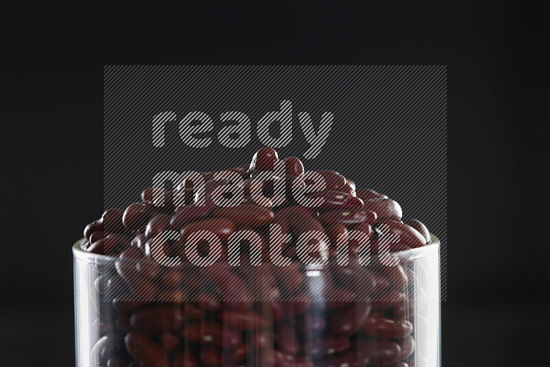 Red kidney beans in a glass jar on black background