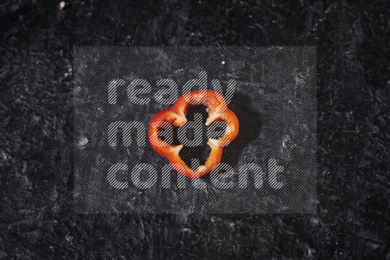 Red bell pepper slices on black background