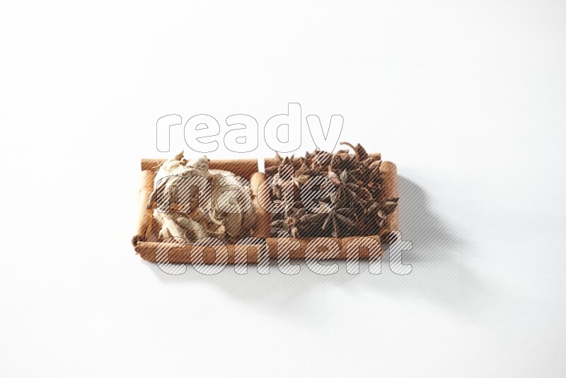 مربعان من أعواد القرفة ممتلئان باليانسون النجمي والزنجبيل المجفف علي خلفية بيضاء