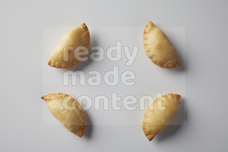 Four fried sambosa from a top angle on a white background