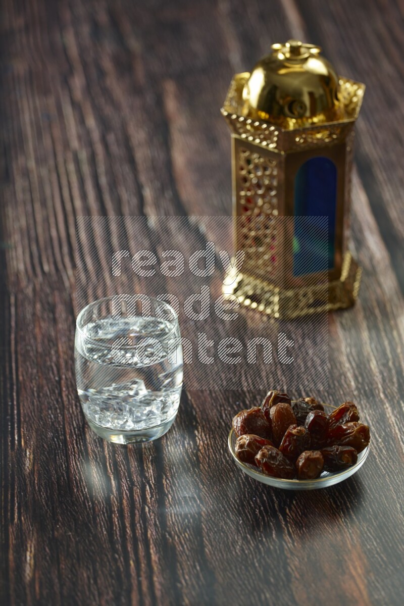 A golden lantern with different drinks, dates, nuts, prayer beads and quran on brown wooden background