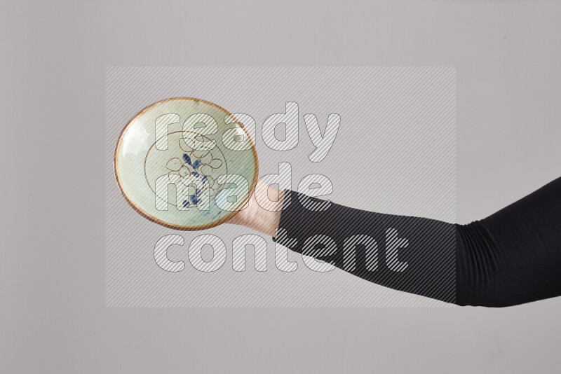 A woman in black abaya holding different pottery essentials in different positions