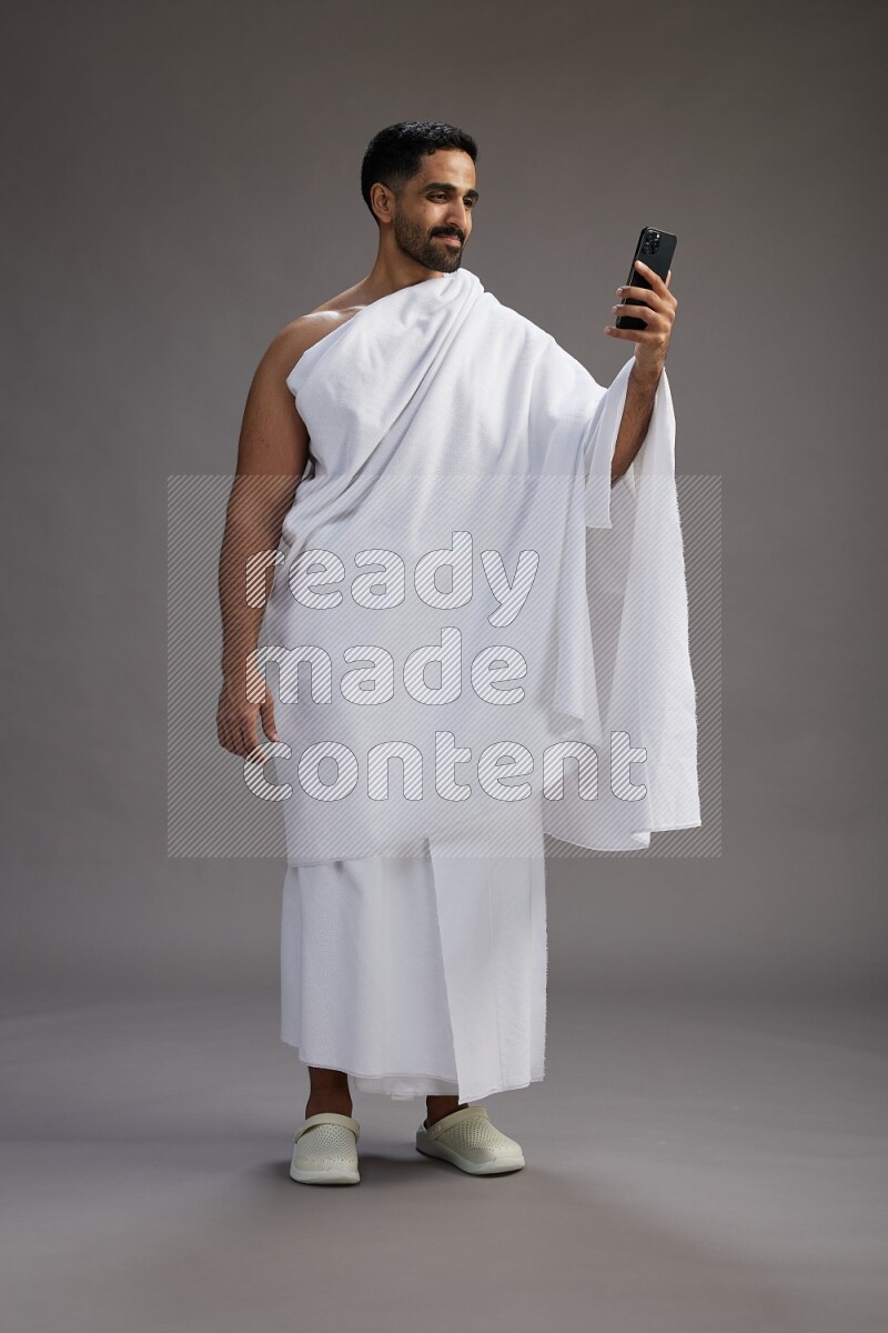 A man wearing Ehram Standing taking selfie on gray background