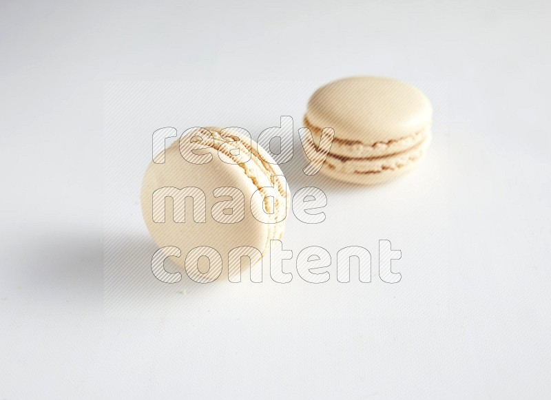 45º Shot of two White Caramel fleur de sel macarons on white background