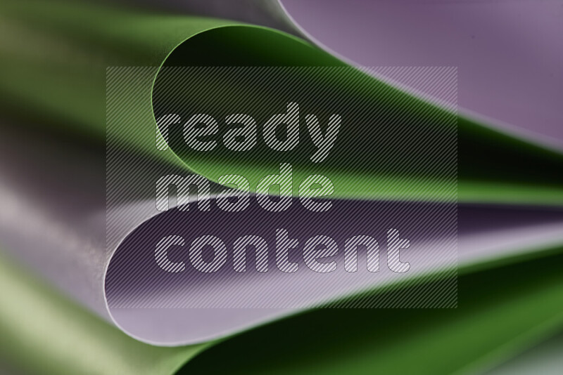 An abstract art showing purple and green paper sheets arranged in an overlapping curves