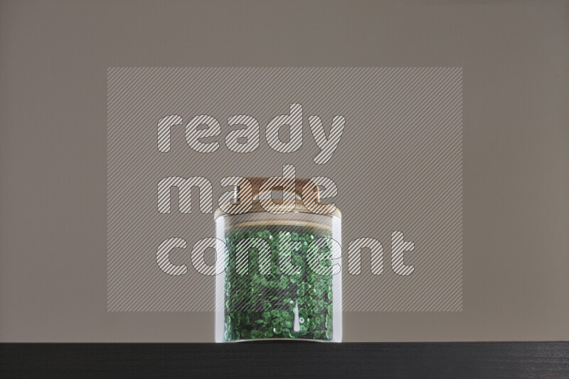 Sequins in a glass jar on black background