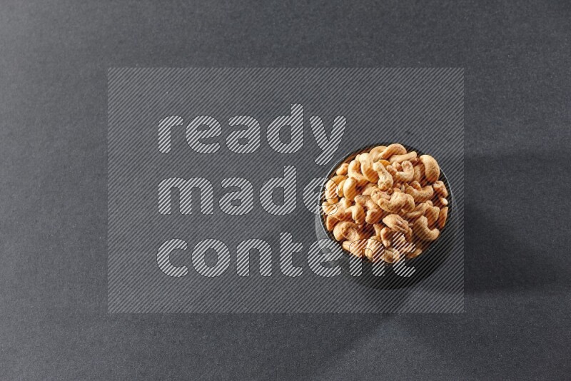 وعاء فخاري أسود ممتلئ بالكاجو على خلفية سوداء