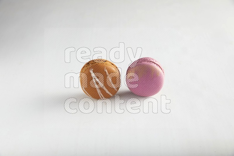 45º Shot of of two assorted Brown Irish Cream, and Purple Strawberry macarons on white background