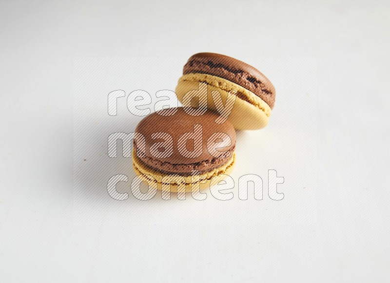 45º Shot of two Yellow and Brown Chai Latte macarons on white background