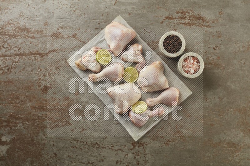 Mixed fresh chicken pieces on a parchment paper direct on a textured rustic background