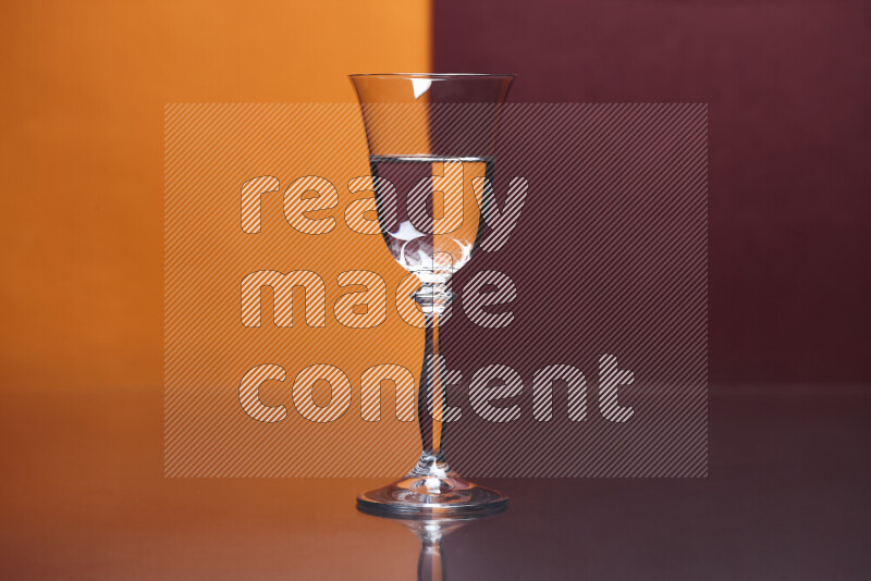 The image features a clear glassware filled with water, set against orange and dark red background