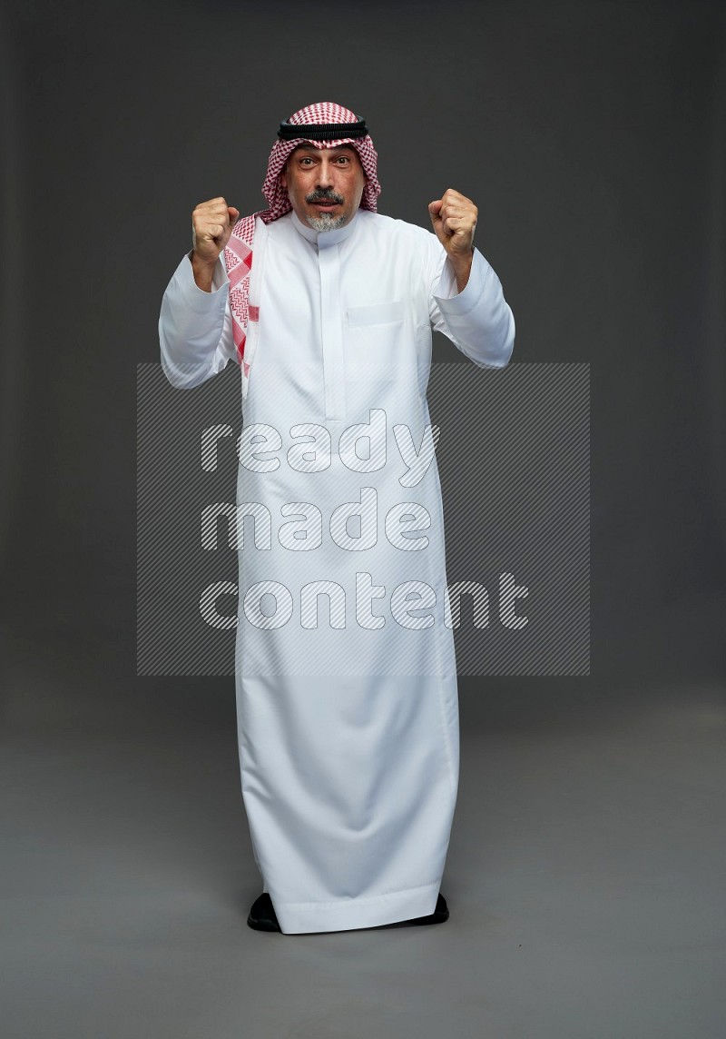 Saudi man with shomag Standing Interacting with the camera on gray background