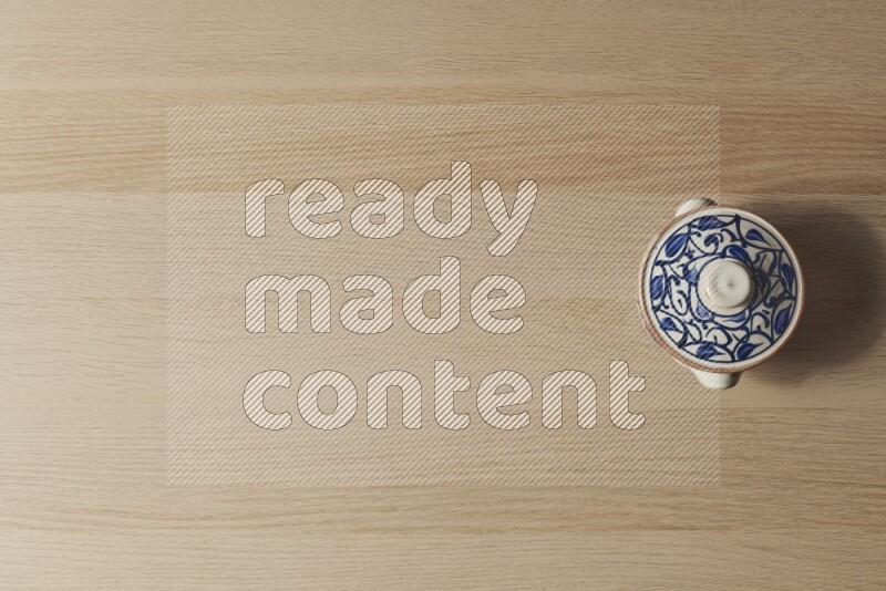 A multicolored pottery pot on light wooden background