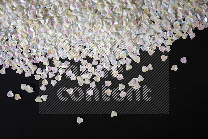 Colorful plastic shards for decoration scattered on a black background