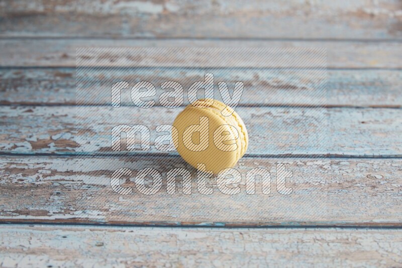 45º Shot of Yellow Vanilla macaron on light blue wooden background
