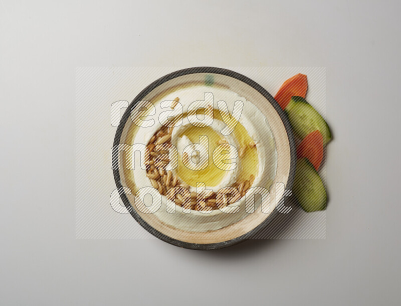 Lebnah garnished with pine nuts in a pottery plate on a white background