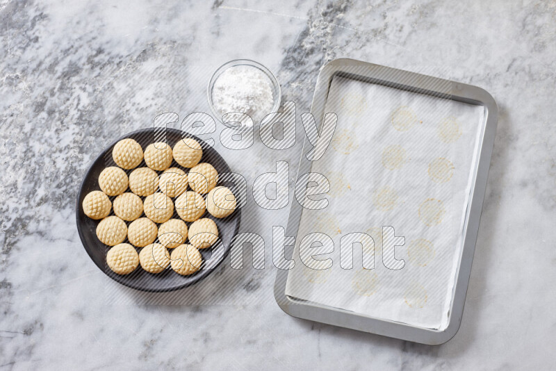 كحك خطوة بخطوة بمكوناته سمن، سكر، دقيق، سمسم، خميرة، ماء ونكهة الكحك على خلفية رخام رمادي