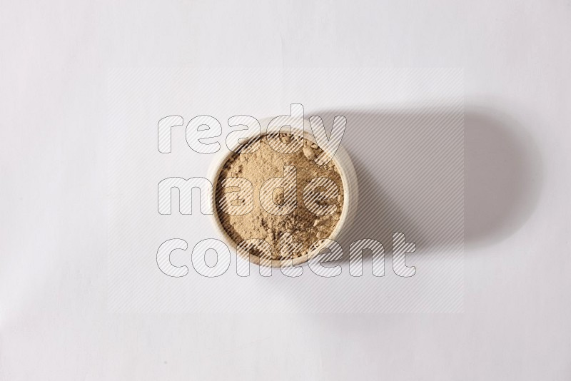 A beige pottery bowl full of garlic powder on a white flooring