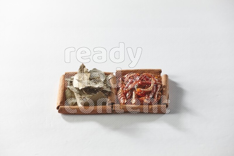 2 squares of cinnamon sticks full of dried red chilis and bay laurel leaves on white flooring