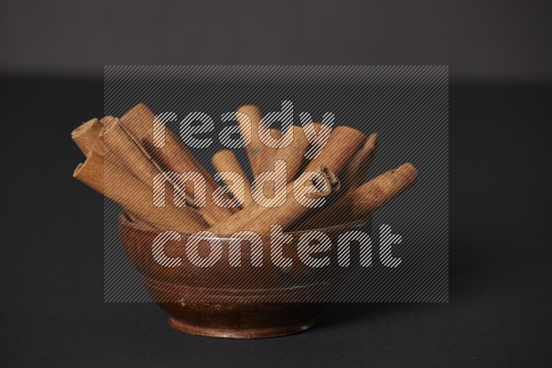 Cinnamon Sticks in a wooden bowl on black background