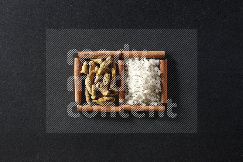 2 squares of cinnamon sticks full of white salt and turmeric fingers on black flooring