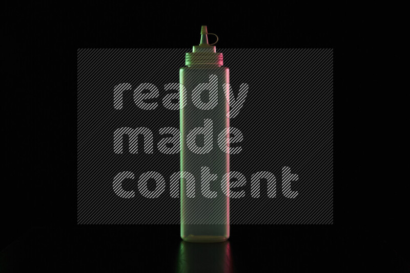 A squeeze bottle with colored rim light against black background