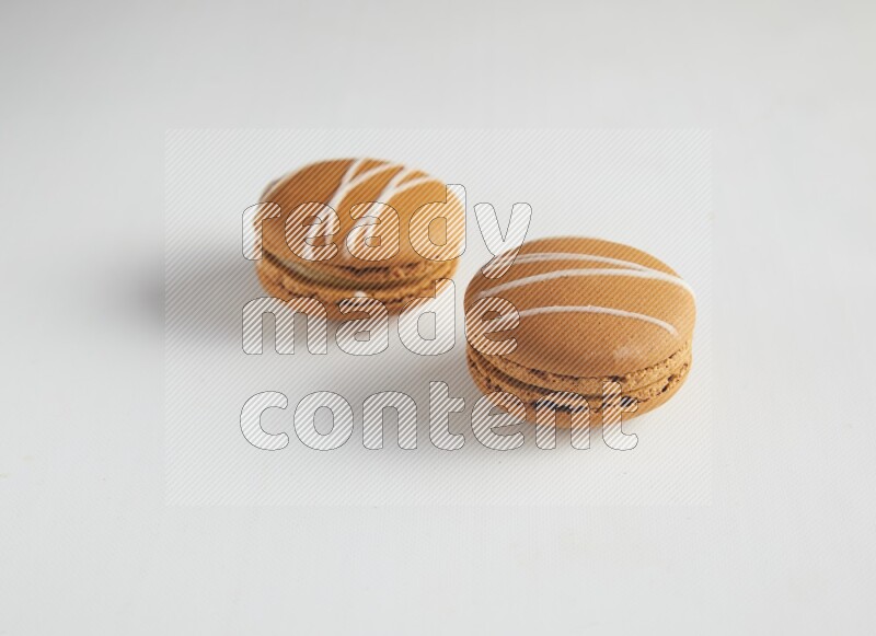 45º Shot of two Brown Irish Cream macarons on white background