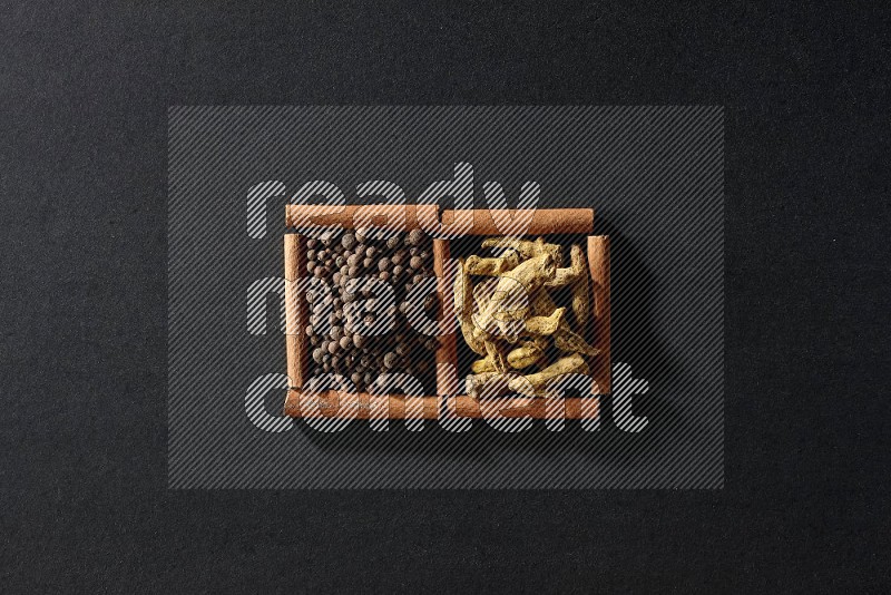 2 squares of cinnamon sticks full of allspice and turmeric fingers on black flooring