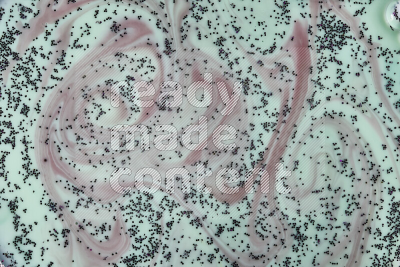 لقطة مقرّبة لدوامات من اللون الأحمر مع بريق أرجواني متلألئ منتشر على خلفية من اللون الأخضر