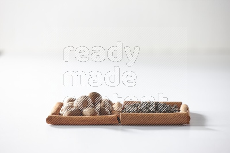 2 squares of cinnamon sticks full of black pepper and nutmegs on white flooring