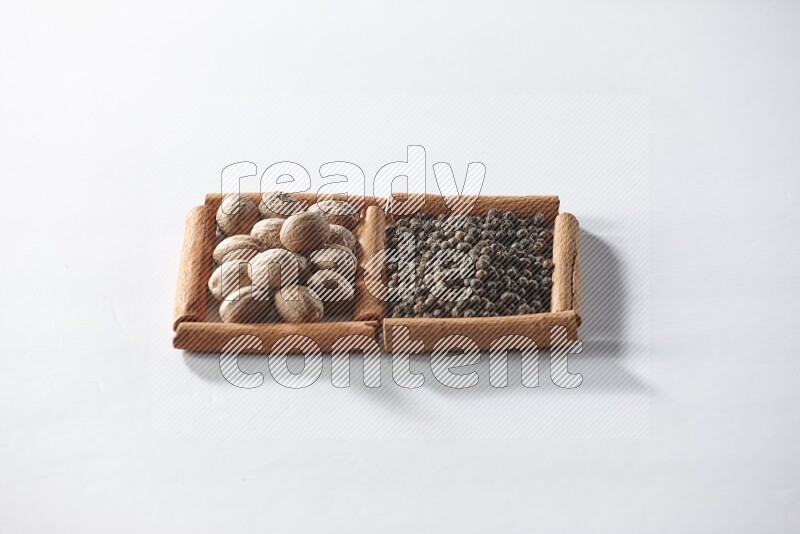 2 squares of cinnamon sticks full of black pepper and nutmegs on white flooring