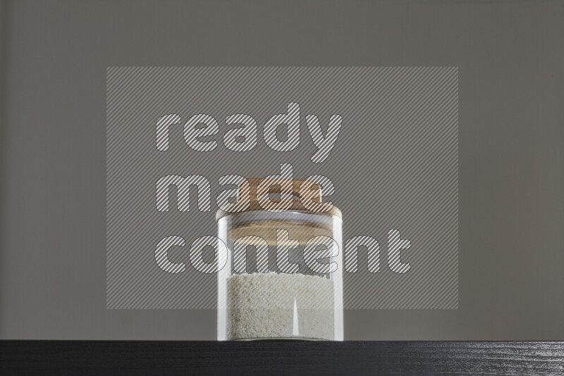 Desiccated coconut in a glass jar on black background