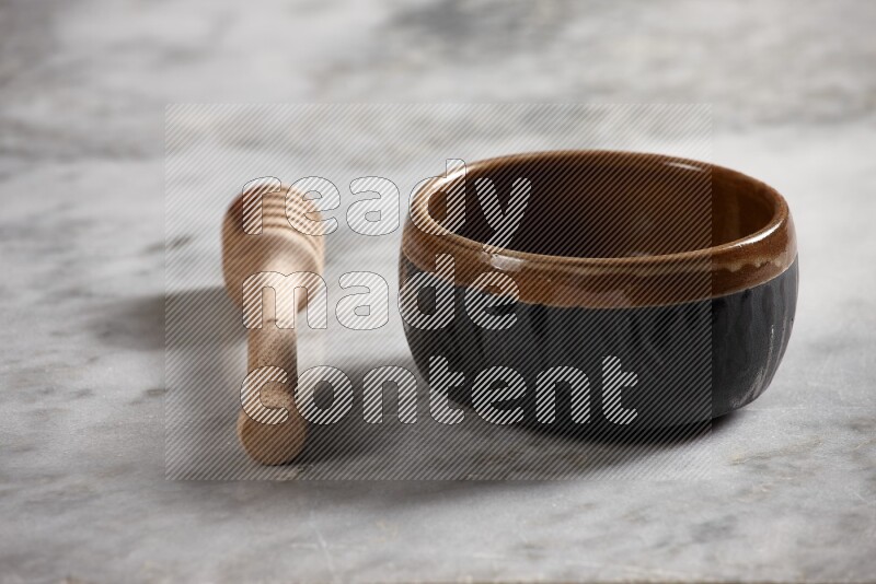 Multicolored pottery bowl with wooden honey dipper on the side on grey marble background