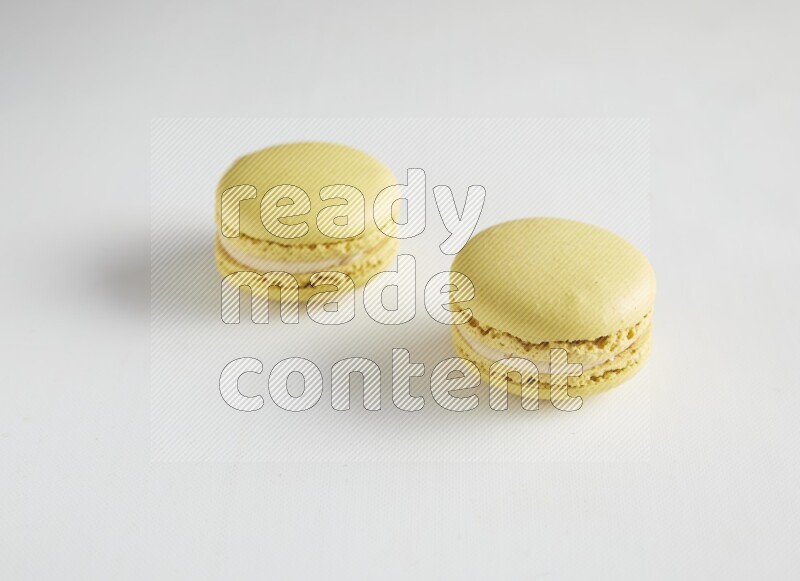 45º Shot of two Yellow Lime macarons on white background