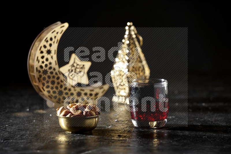 Nuts in a metal bowl with Hibiscus beside golden lanterns in a dark setup