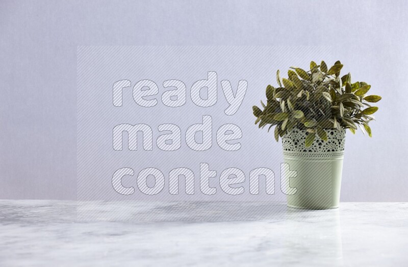 Artificial plant in green decorative pot on grey marble background