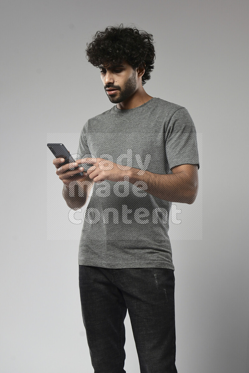 A man wearing casual standing and browsing on the phone on white background