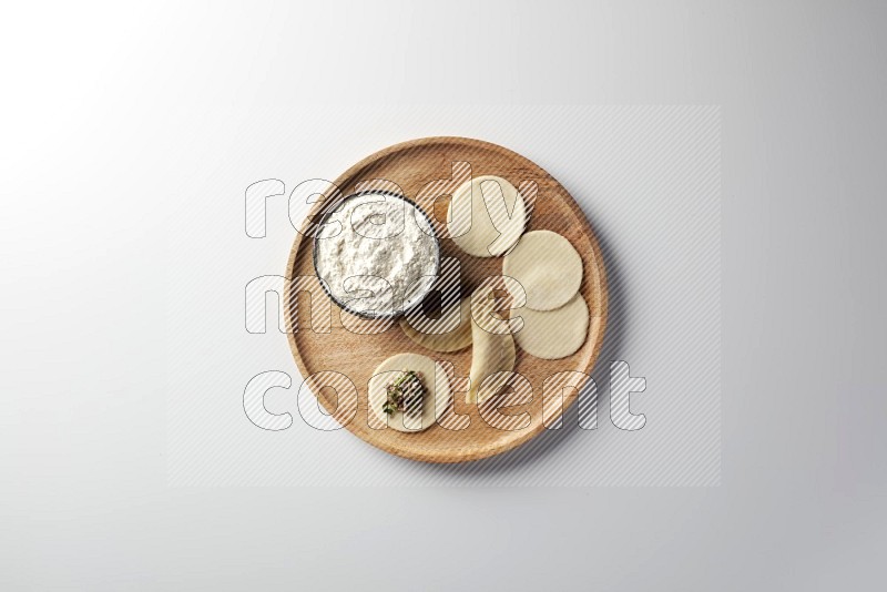 two closed sambosas and one open sambosa filled with meat while flour aside in a wooden dish on a white background