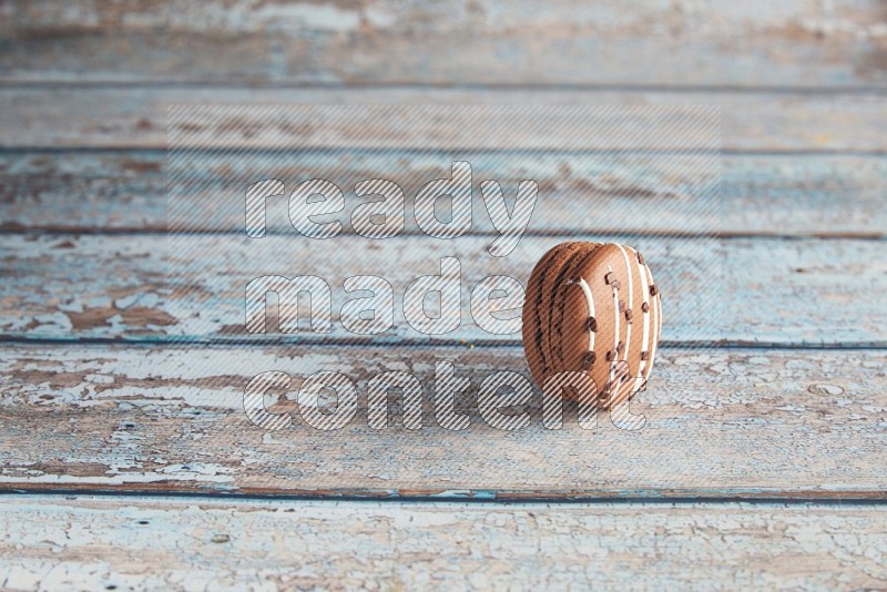 45º Shot of Brown white Chocolate Caramel macaron on light blue wooden background