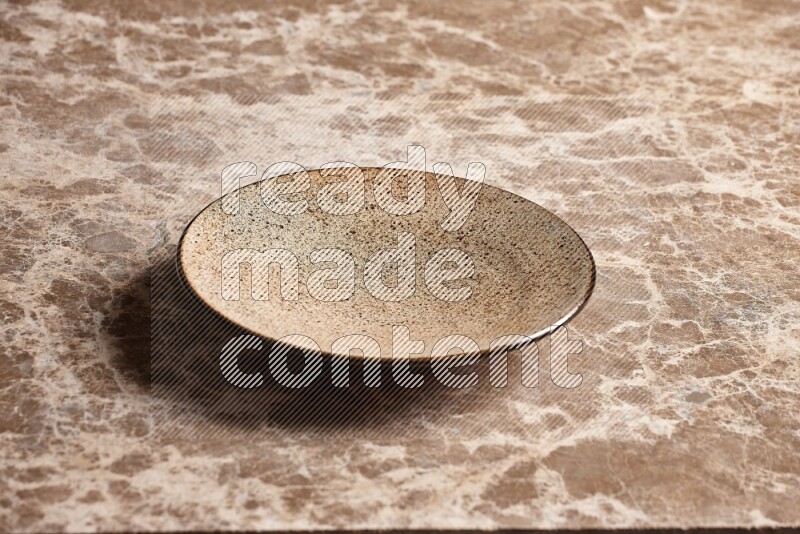 A multicolored pottery plate on beige marble background