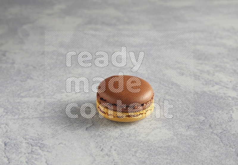 45º Shot of Yellow and Brown Chai Latte macaron on white  marble background